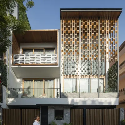 The Screen House façade is a composition of open and screened volumes. The design uses a prominent wooden jaali to provide privacy for the double-height living area while allowing light to filter through, creating a dynamic and modern urban statement.