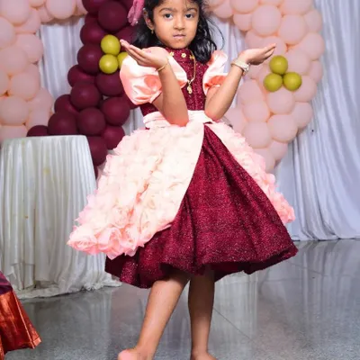 The perfect birthday dress for a little star! This custom party frock features a sparkly maroon bodice, puffed satin sleeves, and a skirt with layers of handmade fabric rosettes for a fun, textured look.