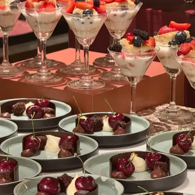 A dessert spread for those who love berries a bit too much. This table features an array of treats, from fresh berry trifles in martini glasses to rich chocolate and cherry cakes.