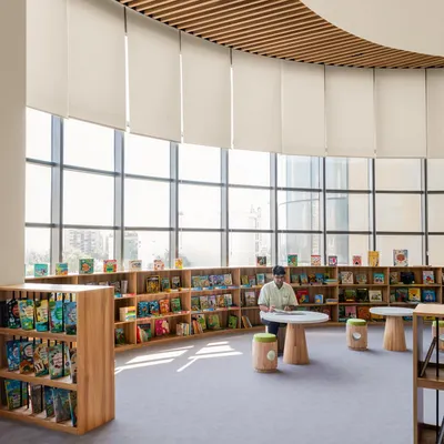 The library at Vedanya School, Gurugram, is a bright, open space with a curved wall of windows. We designed it to be free and supportive, with low, accessible bookshelves and comfortable seating to encourage independent thinking and creativity.