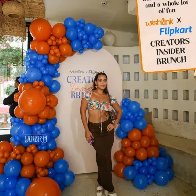An influencer poses in front of the vibrant blue and orange balloon arch we created for the Wishlink x Flipkart Creators Insider Brunch. The custom branded backdrop ensures brand visibility in every photo shared online.