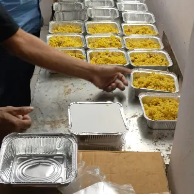 Our efficient assembly line in action, packing fresh yellow rice into aluminum containers for a large order for TATA Hospital.