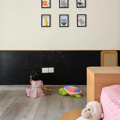 The daughter's bedroom in 'Cover me in Sunshine' is a blush haven with a chalkboard wall for creativity. The platform bed and all furniture are designed to be within a toddler's reach, ensuring the space is both beautiful and accessible.