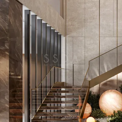 This staircase is designed as a sculptural feature, with golden accents that shimmer against the neutral stone palette. Lush greenery beneath softens the formality, infusing the space with freshness and calm.