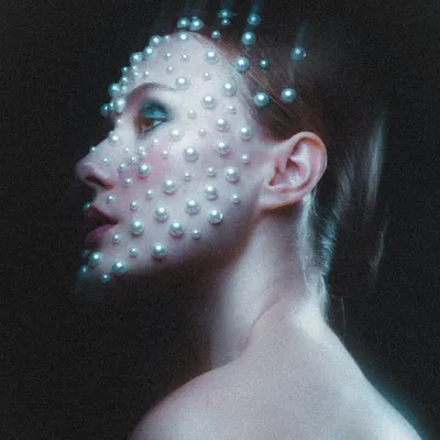 A profile view of the celestial pearl makeup, showing how the pearls catch the light and create dimension. The look was finished with a subtle blue-green eyeshadow and a soft pink lip to complement the cool tones of the lighting.
