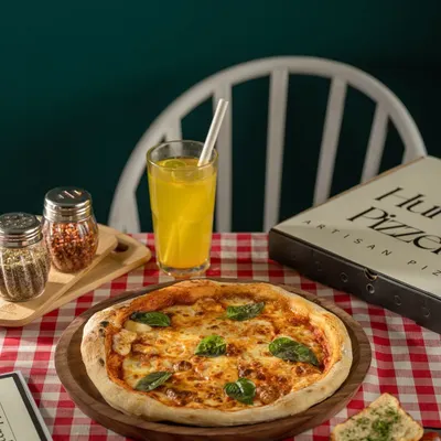 A classic Margherita pizza for The Humble Pizzeria, set in a traditional cafe scene with a red checkered tablecloth. This shot evokes a sense of authentic, comforting Italian-American dining.