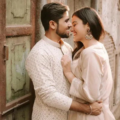 An intimate and happy moment shared between a couple in the rustic lanes of Old Delhi. The warm light and textures of the old door create a beautiful, romantic atmosphere.