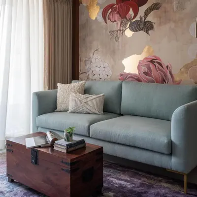 The 'Native Grace' mural, featured in Elle Decor, serves as the heart of this living room. The artwork combines fuchsia, peonies, and hydrangeas with touches of gold leaf, creating a piece that is both elegant and expressive.