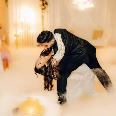 A dramatic dip on the dance floor, surrounded by theatrical smoke. This shot captures the peak of the couple's first dance performance, full of passion and flair.