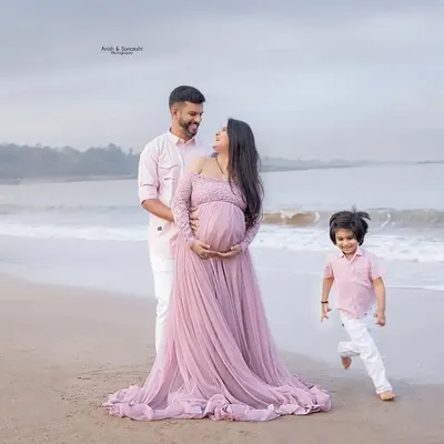 A beautiful family of three, soon to be four, enjoying a quiet moment on the beach. We love capturing these maternity announcement photos with the whole family.