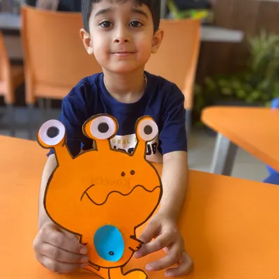 A student proudly holds up the colorful alien he made. Our craft sessions let children bring their wildest ideas to life while practicing fine motor skills.