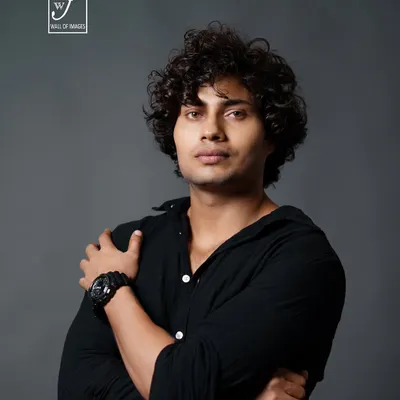 A strong male headshot. The direct eye contact and crossed arms convey confidence, while the studio lighting defines his facial structure.