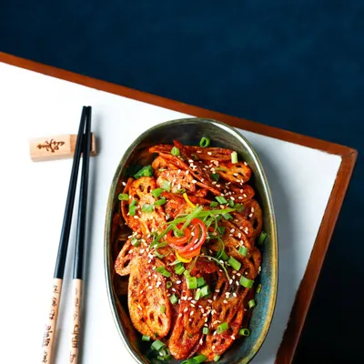 Crispy honey chilli lotus stem, shot with a dark, moody aesthetic to highlight its texture and colour.