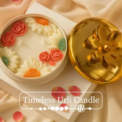 My Timeless Urli Candle, unlit to show the intricate detail of the hand-sculpted wax roses and daisies. It sits beautifully in a reusable container with a golden floral lid, making it a perfect festive decor item.