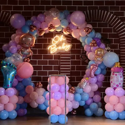 An "Oh Baby" themed baby shower setup. The circular balloon arch with a neon sign creates a perfect photo backdrop. We included baby-themed foil balloons like bottles and footprints for a playful touch.