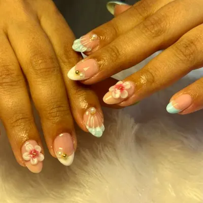 Perfect for a beach vacation, this set features delicate, hand-sculpted seashells and 3D flowers. Accented with tiny pearls and a soft blue French tip, it's a mini seaside escape on your fingertips.