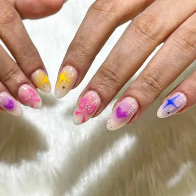 A close-up of the watercolor floral nails, showing the delicate, blended colors and the cute bow and star details that add a playful touch.