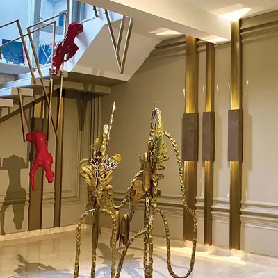 An entryway should be an experience. We used a combination of bold color and luxurious materials, with striking red panther sculptures climbing the custom brass staircase railing and a unique golden console table.
