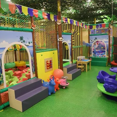 A full view of our vibrant, jungle-themed play area. You can see the foam pit, rockers, merry-go-round, and the multi-level structure, all under a canopy of faux leaves.
