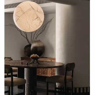 In the 'Aria' project, the dining area is an intimate space tucked behind a candle wall. We designed this African Marble monolith table, which sits under a 'Moon light' fixture, creating a dramatic and otherworldly dining experience.