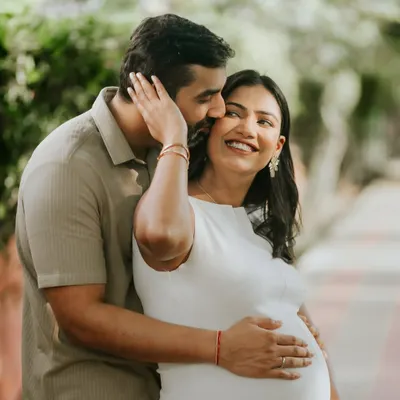 A candid moment of laughter and love during an outdoor maternity shoot. The husband's gentle touch and her joyful smile perfectly capture their excitement.