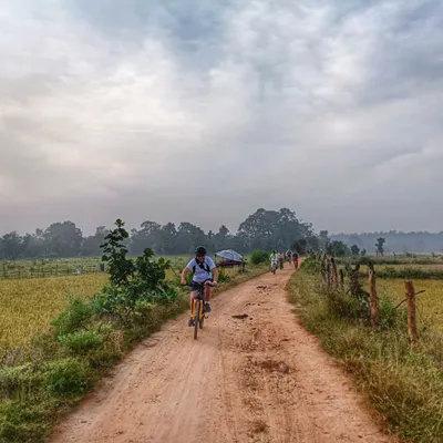 A lone cyclist on a dirt path through the rustic landscape surrounding Kanha National Park. This is what our slow travel philosophy is all about: quiet roads, open spaces, and time to connect with your surroundings.