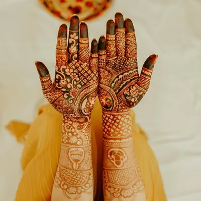 The art of mehndi is a beautiful tradition we love to capture. This detailed shot showcases the intricate henna design on the bride's hands, a symbol of love, joy, and the beginning of a new life.