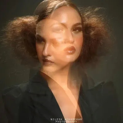 An artistic editorial shot using a double exposure technique. The makeup is glamorous and defined, contributing to the abstract and dreamlike quality of the final photograph.