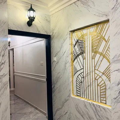 A wider view of the Art Deco inspired entrance, showing how it integrates with the hallway. The classic wall lantern and dark door frame complement the feature wall, creating a cohesive and sophisticated passage.
