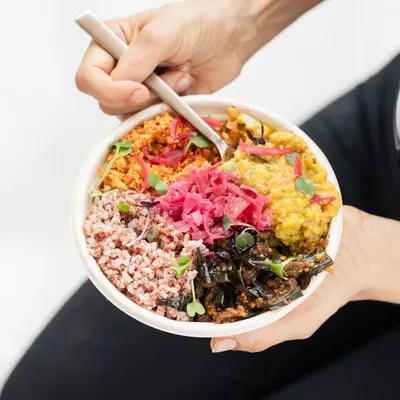 A top-down look at one of our signature bowls. You can see the variety of textures and colours from the red rice, spiced tofu scramble, fresh microgreens, and house-made pickled cabbage.