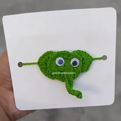 This playful green elephant wristband is made with soft yarn and features fun googly eyes. It's a comfortable and cute accessory for kids to wear.