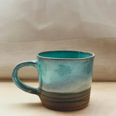 The Flow Mug, designed for slow sipping. This piece features a beautiful ocean-blue glaze over a textured, earth-toned base, complete with a comfortable handle for your morning brew.