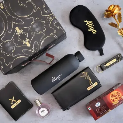 This all-black themed gift set for her is the definition of chic. It includes a personalized water bottle, clutch, passport holder, keychain, and eye mask, plus perfume and cookies, all elegantly arranged.