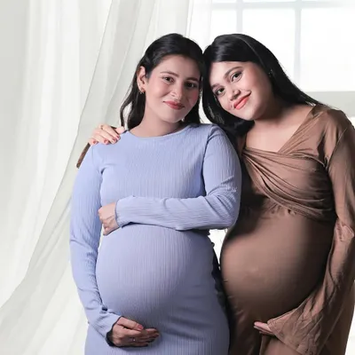 A heartwarming portrait of two expecting sisters. This photo captures the special bond they share during this unique time in their lives, standing together with their baby bumps.