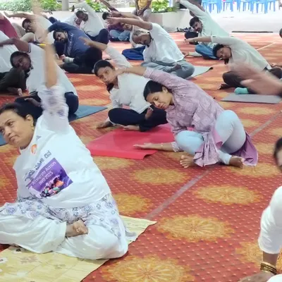 Participants at a BSNL corporate event engage in a seated side stretch. My sessions are designed to be inclusive, offering modifications so that every employee can participate comfortably from their mat.