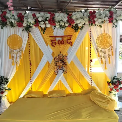 A traditional Haldi seating arrangement with bright yellow and white drapes. We've added bohemian-style dreamcatchers and floral arrangements to create a festive look.