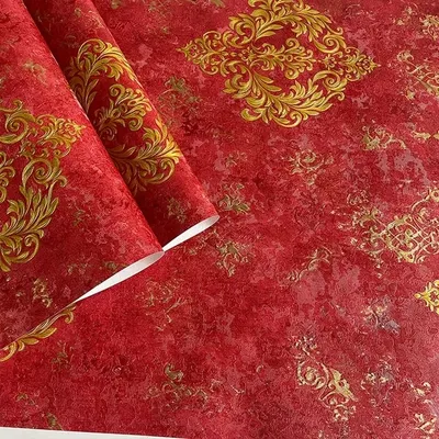 A stunning close-up of a bold red wallpaper with a traditional gold damask pattern, showing its rich color and texture.