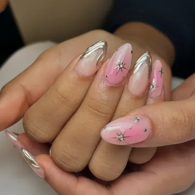 This look is out of this world. It combines a soft pink ombre base with bold silver chrome details and sparkling star-shaped gems for a truly celestial vibe.