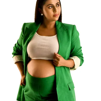 A bold and confident maternity portrait. The mother-to-be wears a striking green suit with her baby bump proudly displayed, showcasing a modern and powerful approach to maternity style.