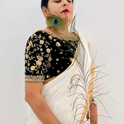 Celebrating Janmashtami with a beautiful black velvet blouse featuring intricate gold and silver embroidery, paired with a simple white saree.