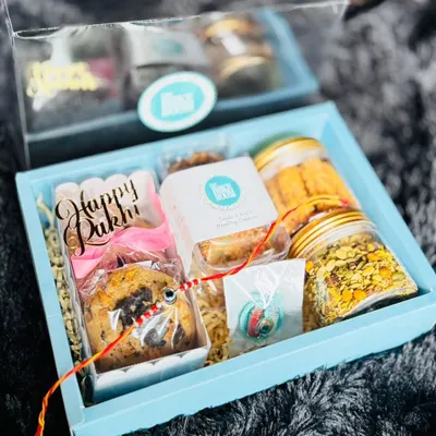 A beautiful Rakhi hamper packed with a variety of our treats. This box includes cookies, savory snacks, and a "Happy Rakhi" chocolate bar, making it a complete gift for your sibling.