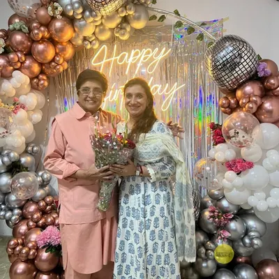 We were honored to create this glamorous backdrop for Kiran Bedi's birthday. The setup featured a "Happy Birthday" neon sign, a shimmering silver curtain, and a lush arch of chrome and white balloons with disco ball accents.