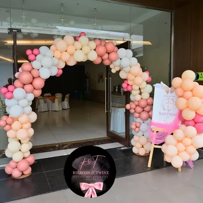 A beautiful balloon arch in shades of peach, pink, and white greets guests at the entrance for baby Sarah's baptism party.