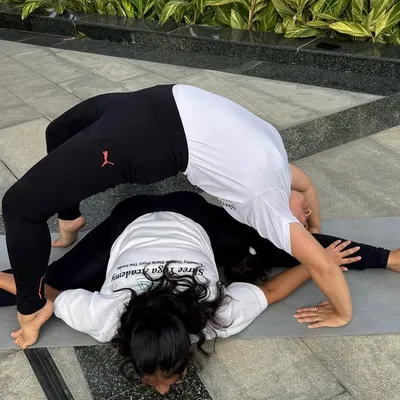 Finding balance together. This partner pose combines a full split (Hanumanasana) with a deep wheel pose (Chakrasana), showcasing the strength and flexibility that comes from consistent practice and mutual support.