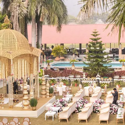 An overview of a stunning lakeside wedding setup at Shikarbadi Hotel, Udaipur. The golden, dome-shaped mandap is the focal point, surrounded by elegant guest seating, creating a picturesque and regal ceremony space.