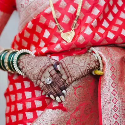 The beautiful dark brown stain of a bridal mehandi, pictured against a traditional red saree. The final color is a result of fresh henna and proper aftercare.