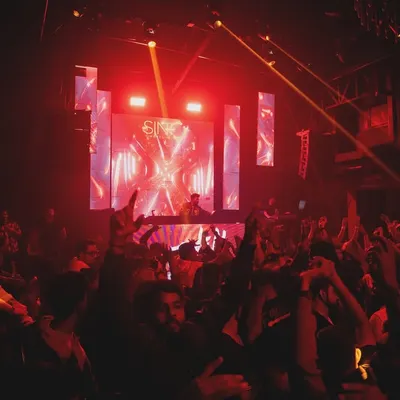 A wide shot of the dance floor at SinQ Nightclub, with everyone's hands in the air. This is the energy I live for.