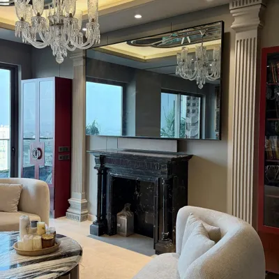 A luxurious living room at Gulshan Dynasty, Noida, featuring our custom-made boucle sofas, a classic black marble fireplace, and a striking red display cabinet. The design blends modern comfort with timeless, classical elements.