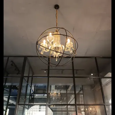 For this dance and fashion studio, we used an industrial-chic aesthetic with exposed ceilings and glass partitions. The statement chandelier, a crystal fixture within a metal orb, adds a touch of glamour to the space.