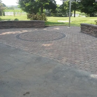 This paver patio features a circular inlay and a curved seating wall. It's a good way to create a distinct area for gathering, especially around a flagpole or other central feature.